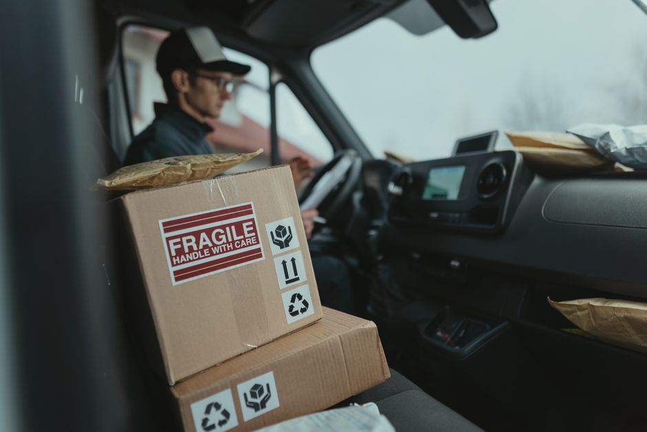 Courier in a delivery van handling fragile packages with care. Ideal for shipping and logistics themes.